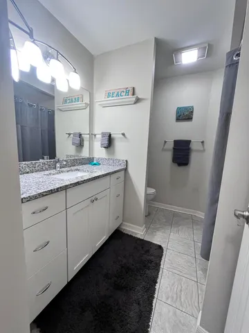 a bathroom with a granite countertop sink a toilet a mirror and vanity