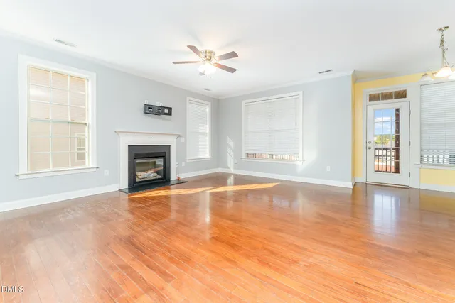 a view of an empty room with window and wooden floor