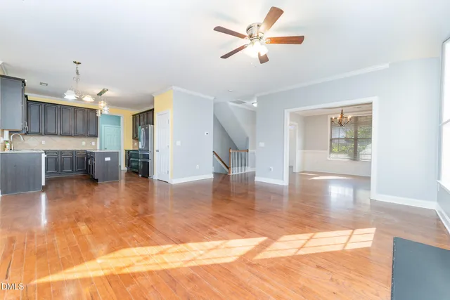 a view of an empty room with kitchen and window