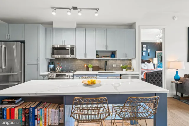 a open kitchen with stainless steel appliances granite countertop a stove top oven a sink a dining table and chairs with wooden floor