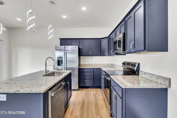 a kitchen with granite countertop a sink a counter space appliances and cabinets