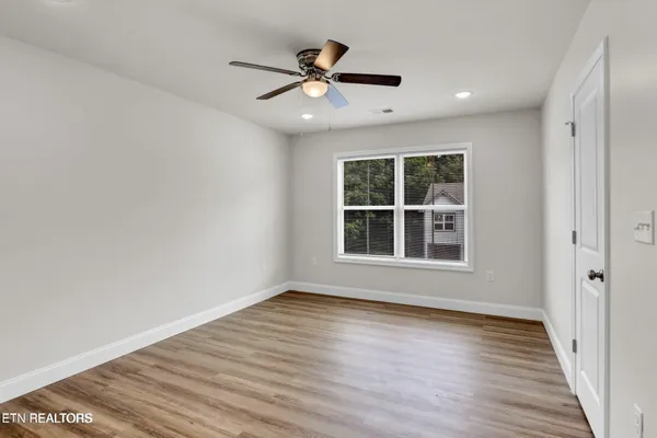 a view of an empty room with wooden floor and a window
