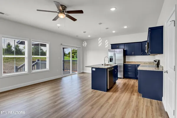 a kitchen with stainless steel appliances granite countertop a refrigerator a sink dishwasher a stove with wooden cabinets and floor