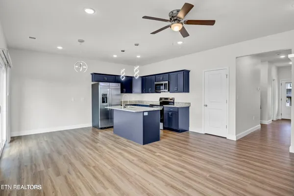 a kitchen with stainless steel appliances kitchen island wooden floors and view living room