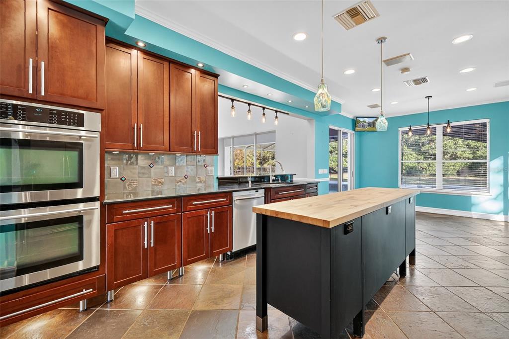 28004 Shirley Shores Road Tavares, FL 32778 - Photo 21 of 68 a kitchen with kitchen island granite countertop a stove top oven a sink and dishwasher a oven with wooden cabinets