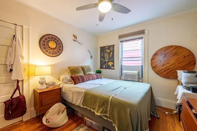 a bedroom with a bed and a lamp on dresser next to a window