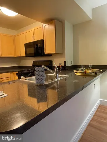 a kitchen with granite countertop a sink a stove and wooden cabinets