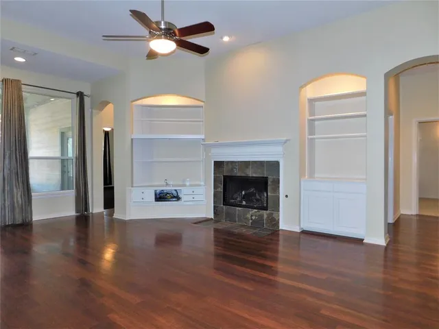 a view of a livingroom with a fireplace a ceiling fan and wooden floor