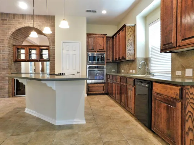 a kitchen with stainless steel appliances granite countertop a stove a sink and a microwave