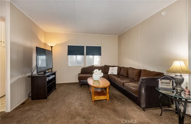 a living room with furniture a flat screen tv and a window