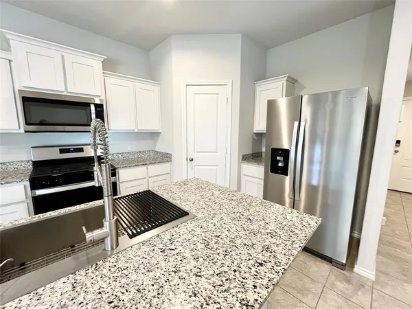a kitchen with granite countertop a refrigerator and a stove top oven