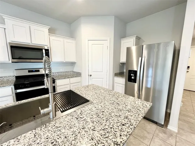 a kitchen with granite countertop a refrigerator and a stove top oven