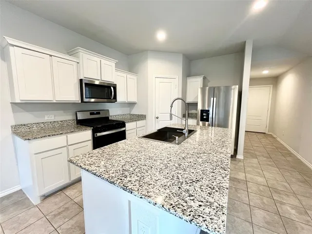 a kitchen with kitchen island granite countertop a stove top oven a sink a counter top space cabinets and a window