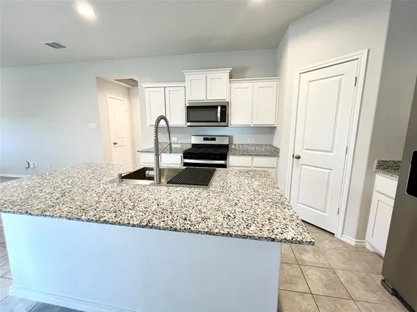 a kitchen with stainless steel appliances granite countertop a stove microwave and sink