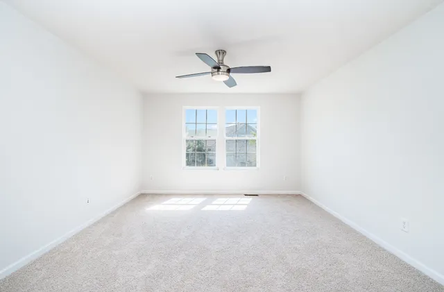 an empty room with windows and fan