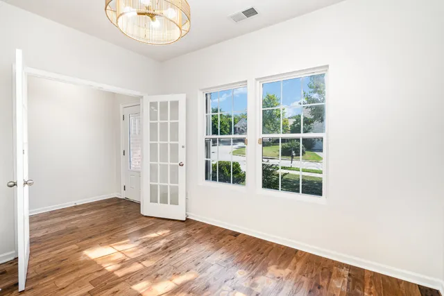 an empty room with wooden floor and windows
