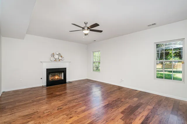 an empty room with wooden floor a fireplace and windows