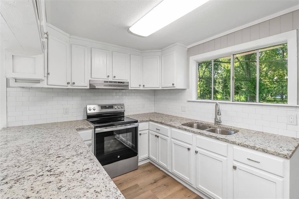 224 Prysock Road Doyline, LA 71023 - Photo 12 of 38 Kitchen featuring electric range, white cabinets, light wood-style floors, light stone countertops, and tasteful backsplash