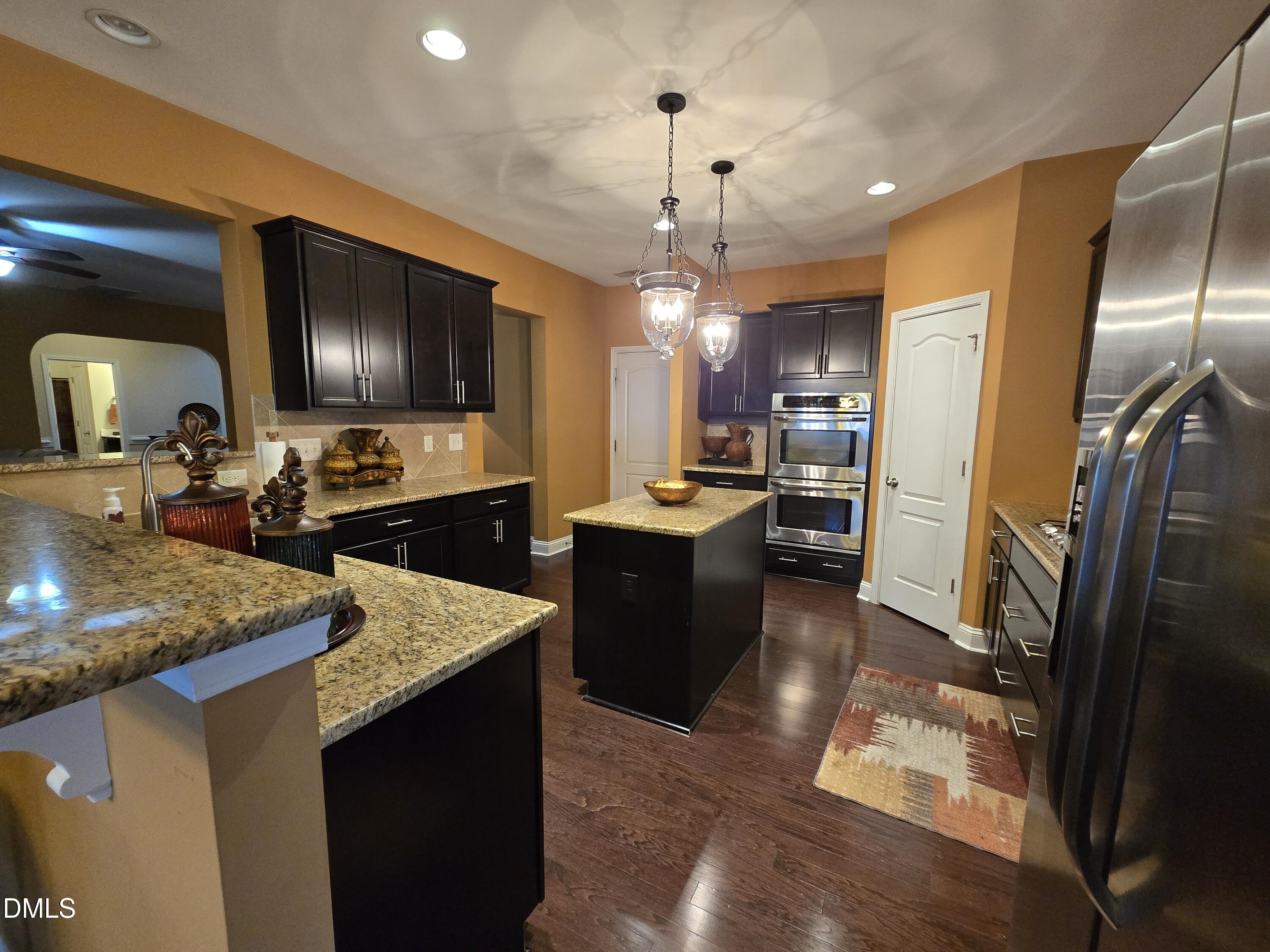 4202 Smithson Court Raleigh, NC 27616 - Photo 15 of 54 a kitchen with stainless steel appliances kitchen island granite countertop a refrigerator a sink a stove and oven