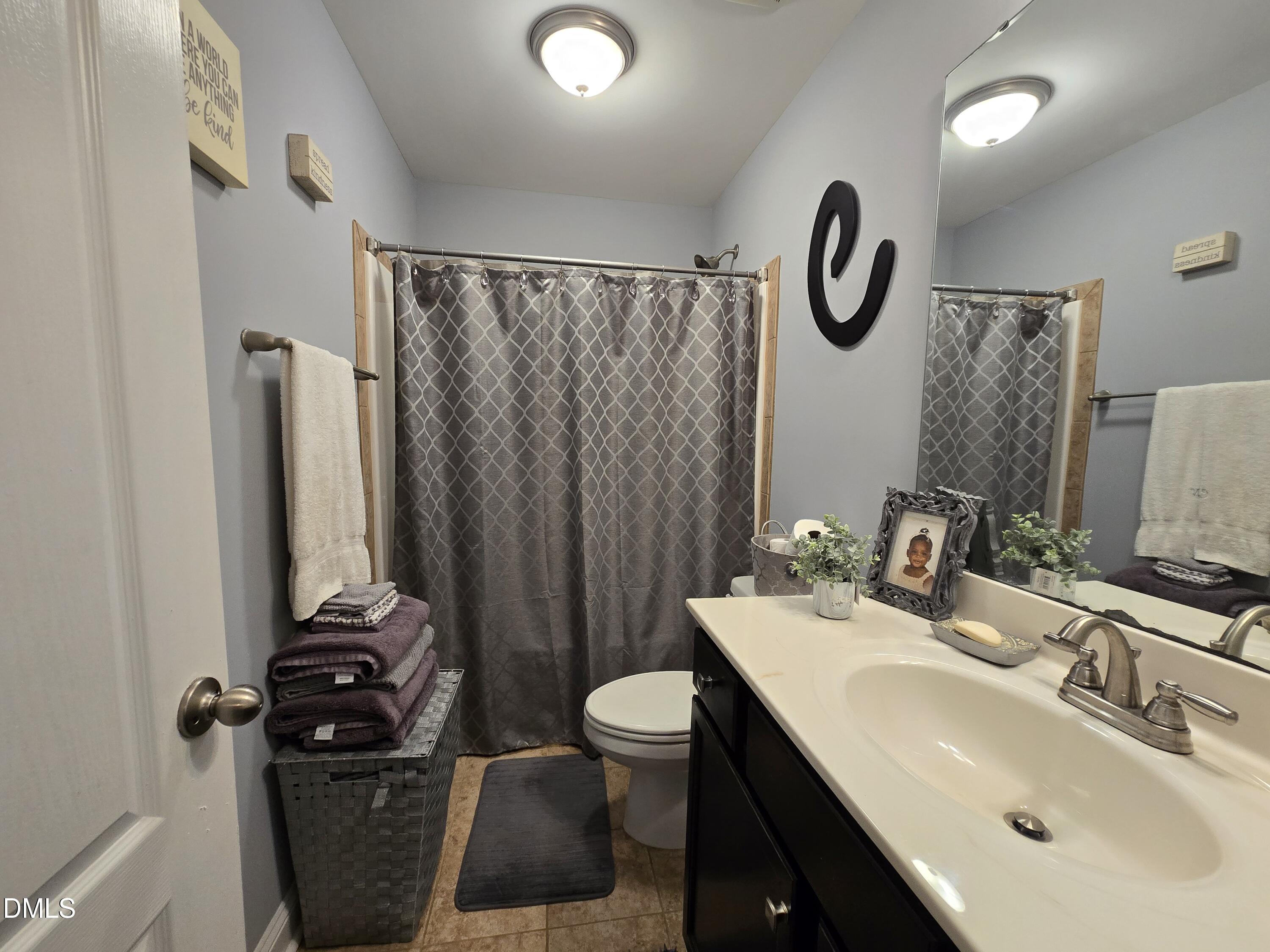 4202 Smithson Court Raleigh, NC 27616 - Photo 30 of 54 a bathroom with a sink a toilet a mirror and shower curtain