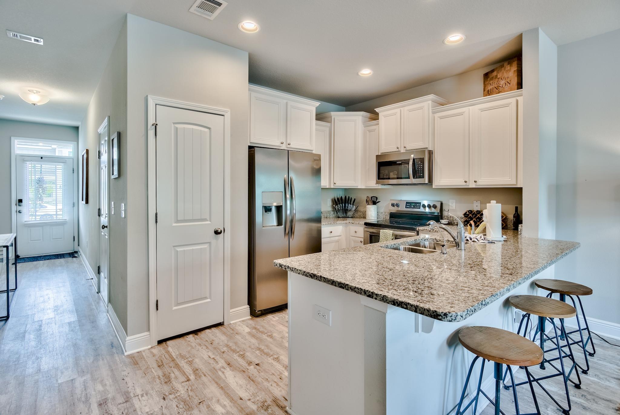 89 Crossing Lane, Unit C Santa Rosa Beach, FL 32459 - Photo 11 of 27 a kitchen with stainless steel appliances granite countertop a refrigerator a stove a sink a dining table and chairs