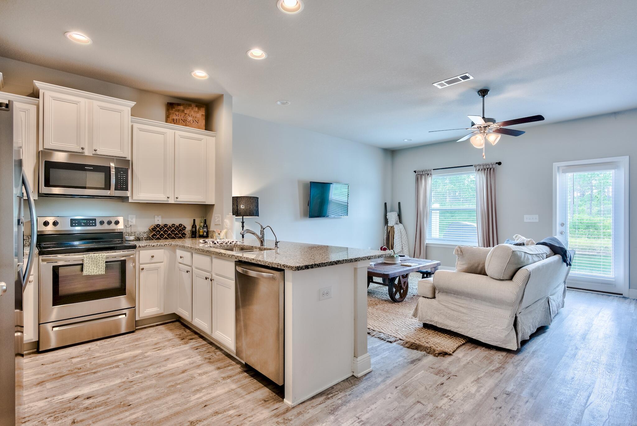 89 Crossing Lane, Unit C Santa Rosa Beach, FL 32459 - Photo 3 of 27 a open kitchen with stainless steel appliances granite countertop a stove top oven a sink dishwasher and a microwave oven with wooden floor