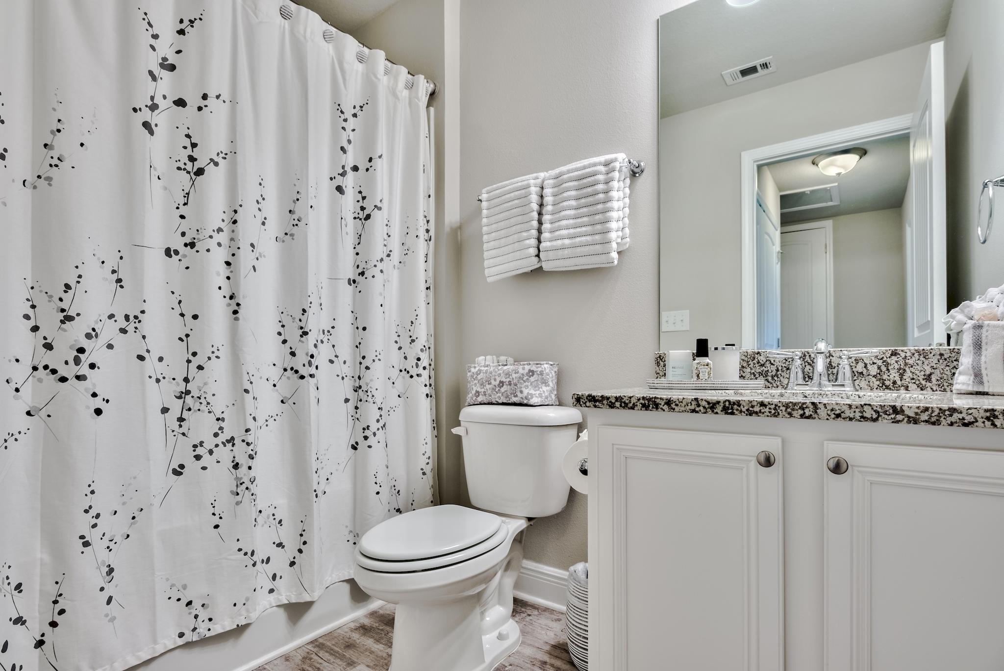 89 Crossing Lane, Unit C Santa Rosa Beach, FL 32459 - Photo 25 of 27 a bathroom with a granite countertop toilet a sink a mirror and a shower