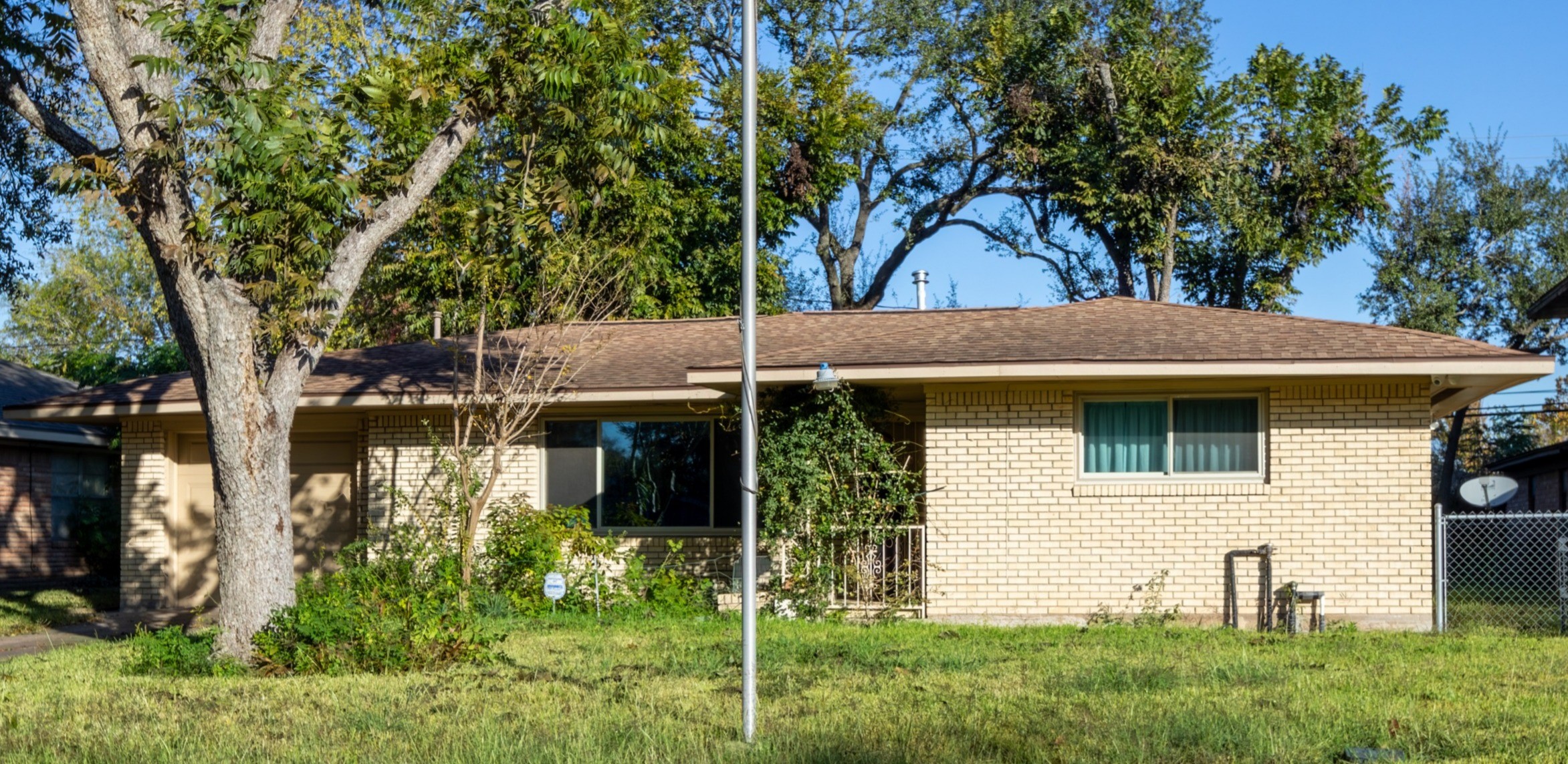a view of house with a yard and a large tree