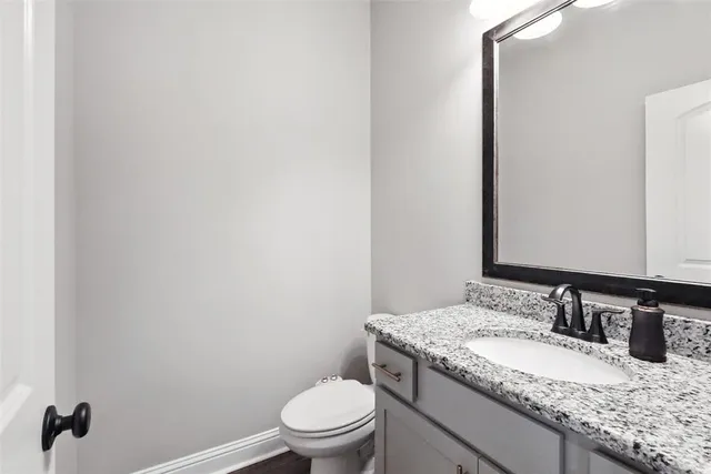 a bathroom with a granite countertop sink toilet and mirror