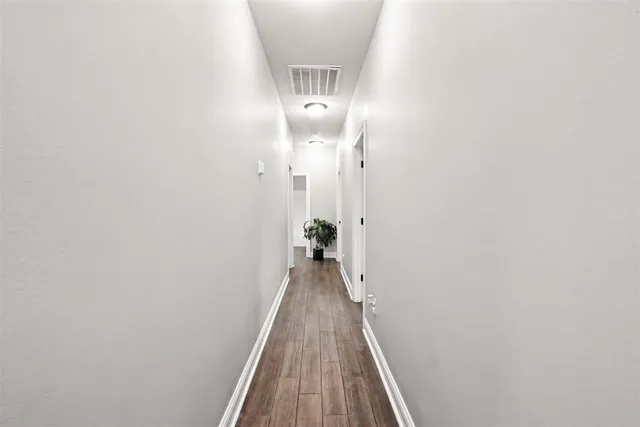 a view of a hallway with wooden floor and a bathroom