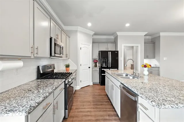 a large kitchen with stainless steel appliances granite countertop a lot of counter space and wooden floor