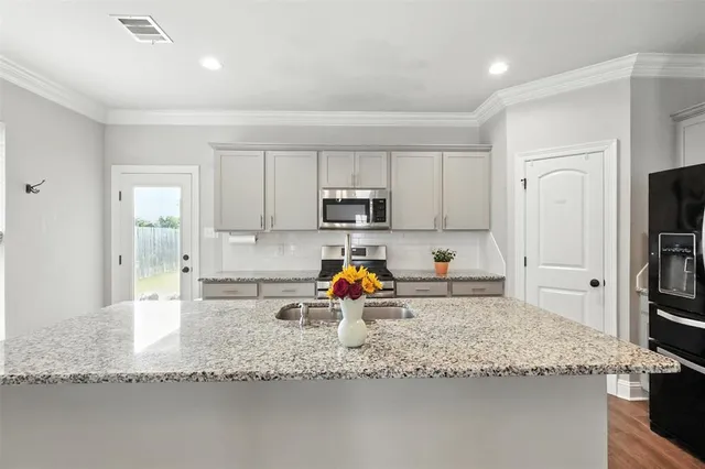 a kitchen with granite countertop a sink stove and refrigerator