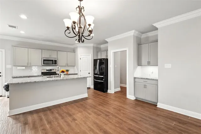 a kitchen with stainless steel appliances granite countertop a refrigerator a stove top oven a sink and dishwasher with wooden floor