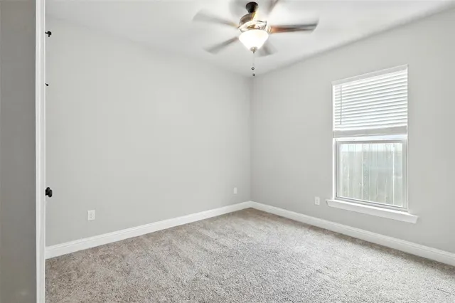 an empty room with a window and a fan