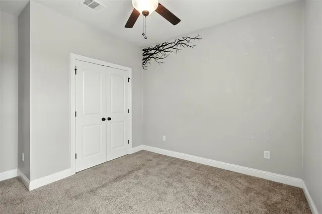 an empty room with a ceiling fan and carpet