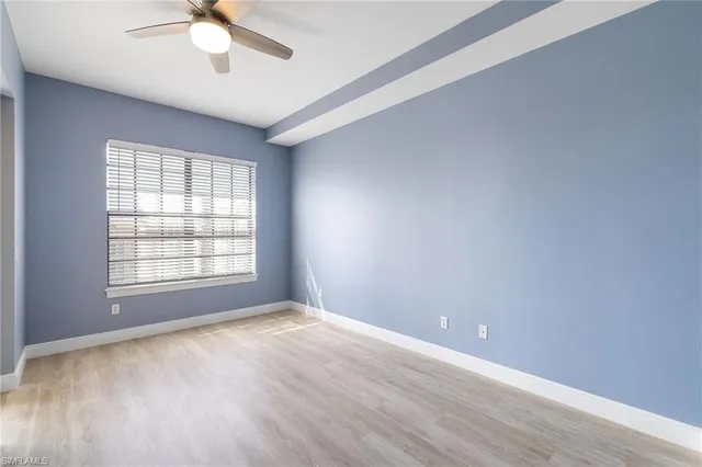 an empty room with a window and a fan