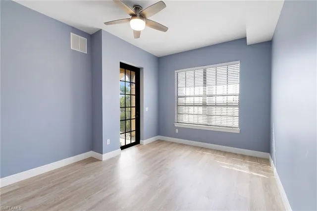 a view of an empty room with a window and wooden floor