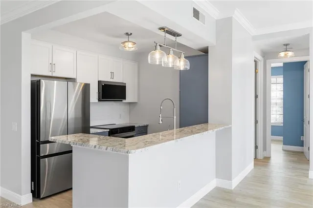 a kitchen with stainless steel appliances granite countertop a refrigerator a stove a sink dishwasher and a refrigerator with wooden floor