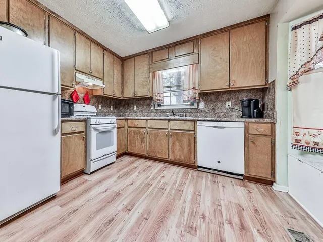 a kitchen with stainless steel appliances granite countertop a hardwood floor sink stove and white cabinets