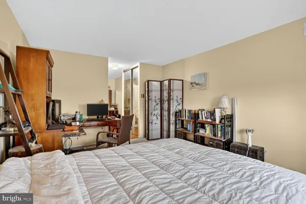 a bedroom with a bed a large mirror and a flat tv screen on a dresser