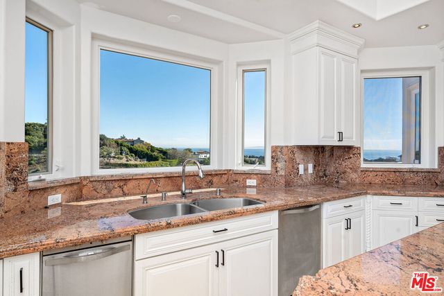 a kitchen with granite countertop a sink and white cabinets