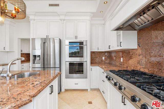 a kitchen with stainless steel appliances granite countertop a stove a sink and a refrigerator
