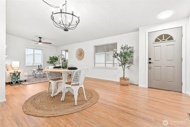 a dining room with wooden floor a chandelier a wooden table and chairs