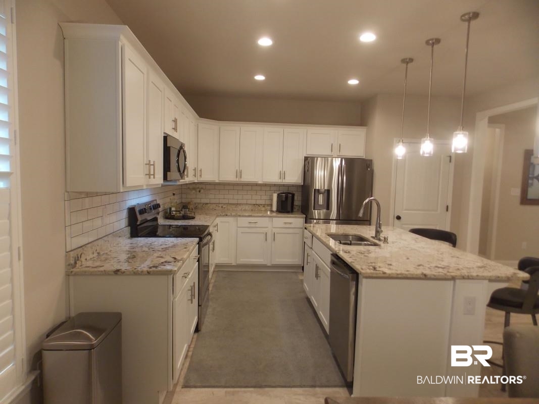 1121 Stella Road Foley, AL 36535 - Photo 7 of 22 Kitchen with pendant lighting, an island with sink, white cabinets, sink, and stainless steel appliances
