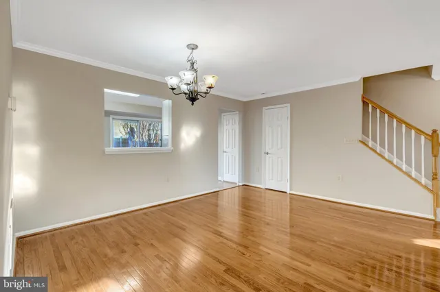 a view of an empty room with wooden floor and a chandelier