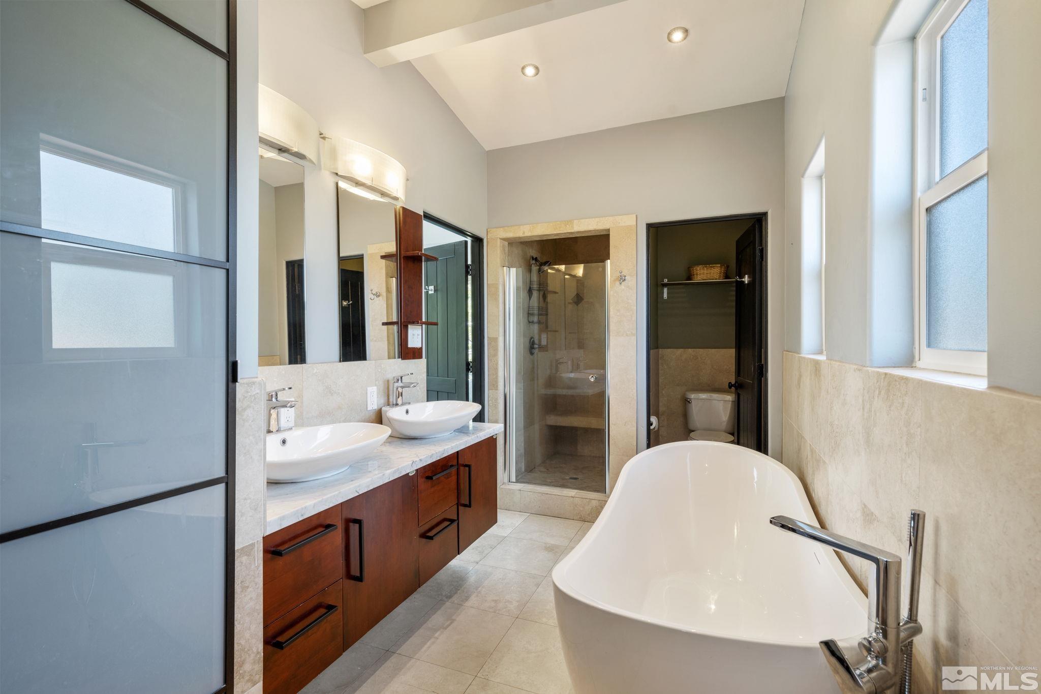 1005 Memory Lane Reno, NV 89509 - Photo 16 of 32 a spacious bathroom with a double vanity sink a mirror and a bathtub
