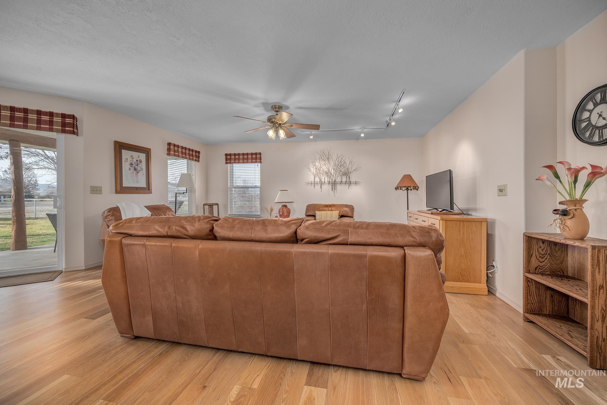 946 Indianhead Road Weiser, ID 83672 - Photo 5 of 36 Living room featuring ceiling fan, light wood-style floors, and rail lighting