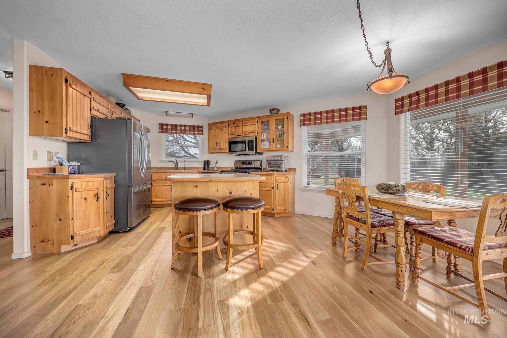 946 Indianhead Road Weiser, ID 83672 - Photo 6 of 36 Kitchen with stainless steel appliances, light wood-style flooring, pendant lighting, and a kitchen bar
