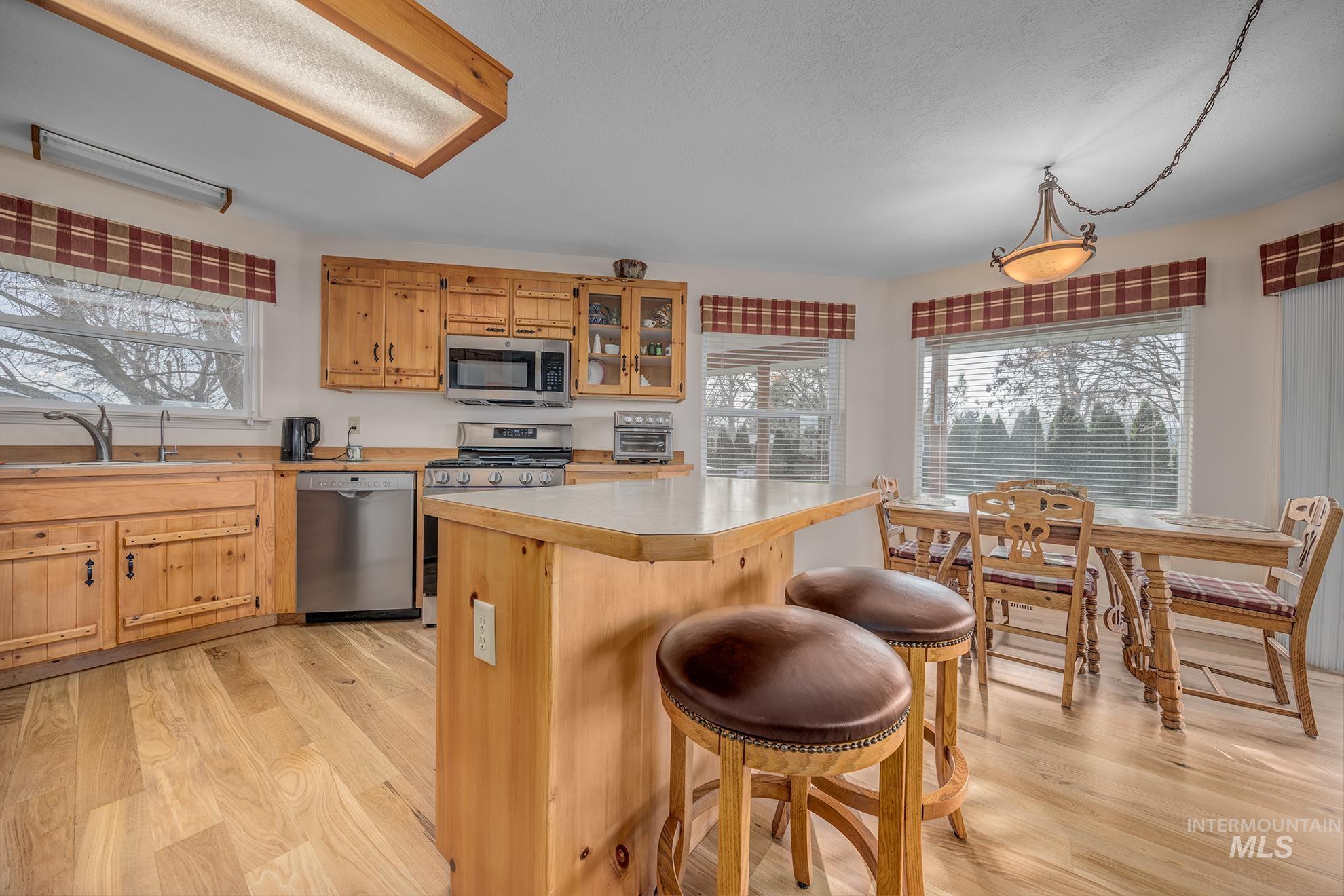 946 Indianhead Road Weiser, ID 83672 - Photo 7 of 36 Kitchen featuring light wood-style flooring, glass fronted cabinets, stainless steel appliances, light countertops, and plenty of natural light