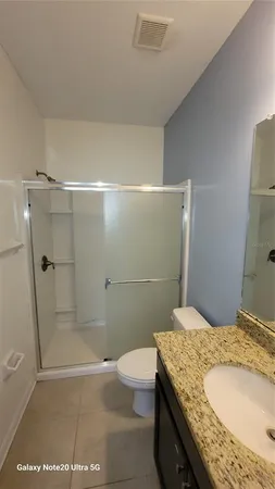 a bathroom with a granite countertop sink a toilet and shower